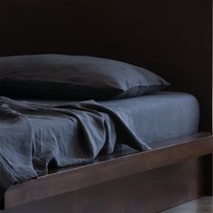 a bed with two pillows on top of it and a blanket over the headboard