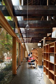 two people sitting on chairs in the middle of a room with bookshelves and shelves