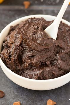 a white bowl filled with brownie batter on top of a black counter next to orange peels