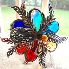 a colorful glass flower sitting on top of a white table next to an open window