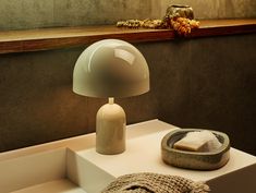 a table lamp sitting on top of a white box next to a bowl and towel