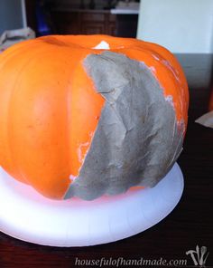 an orange and white pumpkin sitting on top of a table next to a paper plate