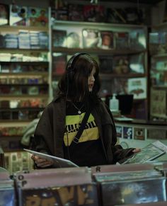 a woman wearing headphones standing in front of a record store counter with records on the shelves