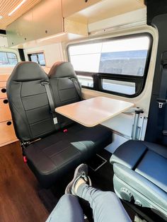 the interior of an rv with two seats and a table on it's side