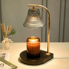 a table lamp with a candle on it next to a book and other items in the background