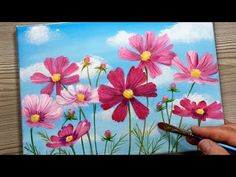 a person is painting flowers on a canvas