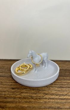 a white plate with a gold ring and a horse figurine on it