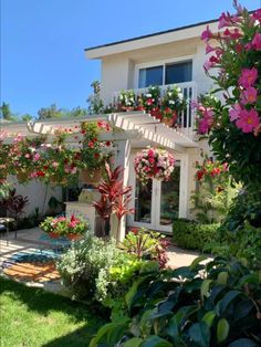 a house with pink flowers on the balcony and landscaping around it, as well as a swimming pool