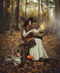 a woman dressed as a witch sitting on a tree stump in the woods holding a lantern