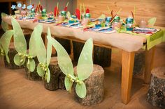 the table is set up with little tinkerbells on top of wood logs