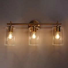 three lights are on the wall with clear glass jars