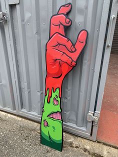 a hand painted on the side of a wall with red and green paint dripping from it