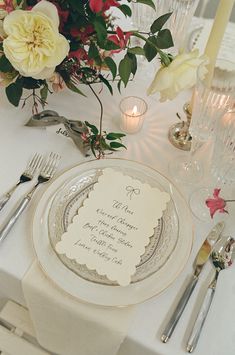 a table set with plates, silverware and flowers