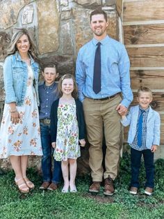 a family poses for a photo in front of a rustic log cabin with their two children