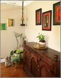 a wooden cabinet sitting on top of a hard wood floor next to a wall covered in pictures