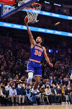 the basketball player is jumping up to dunk the ball in front of an audience