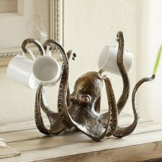 an octopus sculpture with two cups on it's back and one cup in its mouth