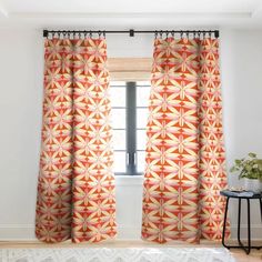 an orange and yellow patterned curtain hangs in front of a window with a white rug on the floor