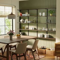 a dining room table with chairs and shelves on the wall