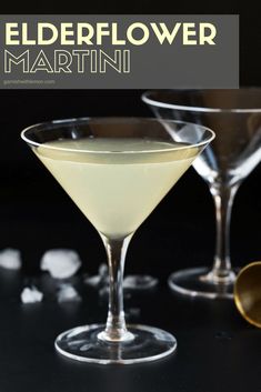 two martini glasses filled with white wine and garnished with ice cubes on a black surface