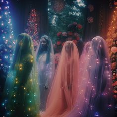 three women dressed in long veils standing next to each other near a christmas tree