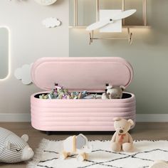 a pink toy chest sitting on top of a rug next to a teddy bear and other toys