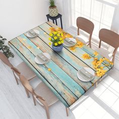 a table with plates and flowers on it in the middle of a room next to a potted plant