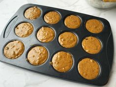 a muffin tin filled with cupcakes on top of a white marble counter