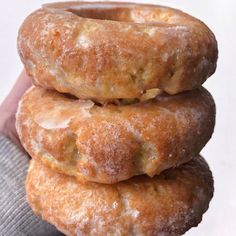 three donuts stacked on top of each other in front of a person's hand