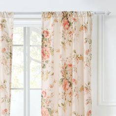 an open window with floral curtains hanging on the side and white walls in front of it