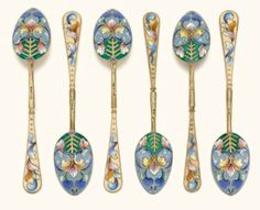 six antique spoons with floral designs are lined up against a white background and one is empty