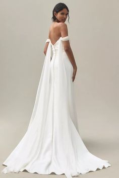 a woman wearing a white wedding dress with an open back