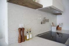 a kitchen with white marble counter tops and wooden utensils on the stove top