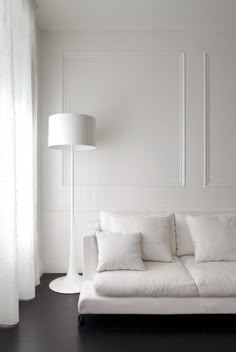 a white couch sitting next to a lamp in a living room