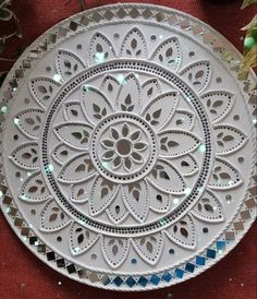 a decorative white plate sitting on top of a red cloth covered floor next to flowers