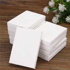 several white square coasters stacked on top of each other with flowers in the background