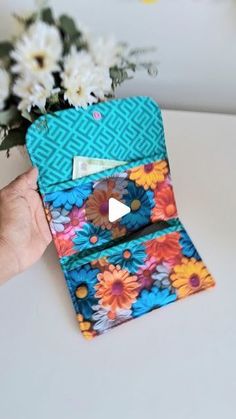 a person is holding a colorful wallet with flowers in it