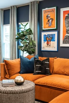 a living room with orange couches and pictures on the wall above them, along with a coffee table