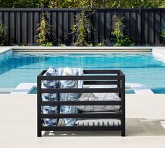 an outdoor lounge chair next to a swimming pool with pillows on the seat and back