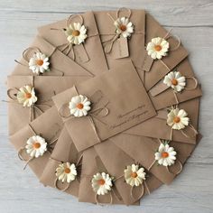 a bunch of brown envelopes with white daisies tied to them on a table