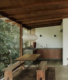 a wooden table sitting under a window next to a kitchen area with a sink and counter top