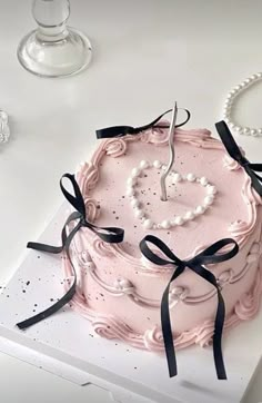 there is a pink cake with pearls on it