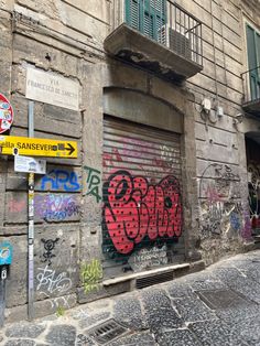 an alleyway with graffiti on the side of it and a street sign next to it