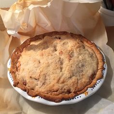 a pie sitting on top of a white plate next to a paper bag filled with food