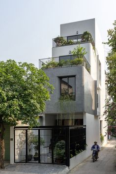 a man riding a motorcycle past a tall building with plants on the balconies