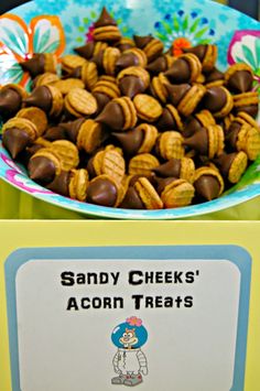 a bowl full of candy cheetos next to a sign that says sandy cheeks'acorn treats