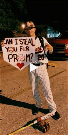 a baseball player holding a sign that says can i steal you for prom?