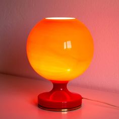 an orange lamp sitting on top of a table next to a pink wall and floor