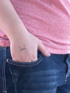 a person with a small cat tattoo on their left side of the arm, showing it's back pocket