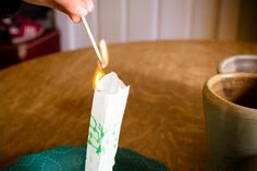 a person lighting a matchstick on top of a paper bag that is sitting on a table